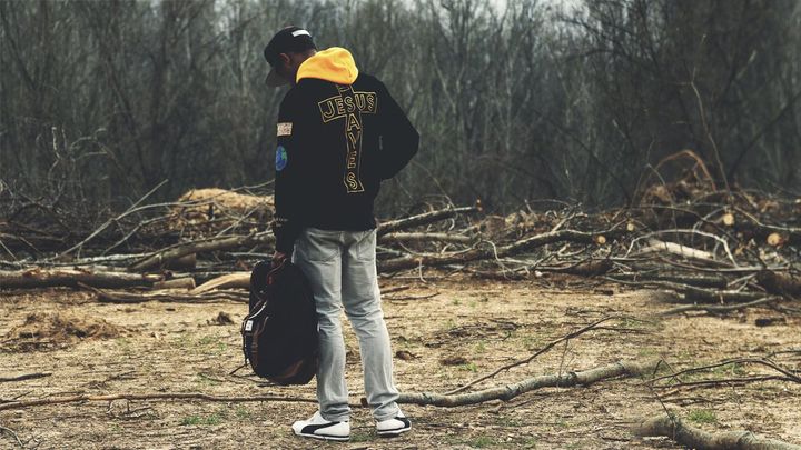 Man standing in a field with a Jesus hoodie