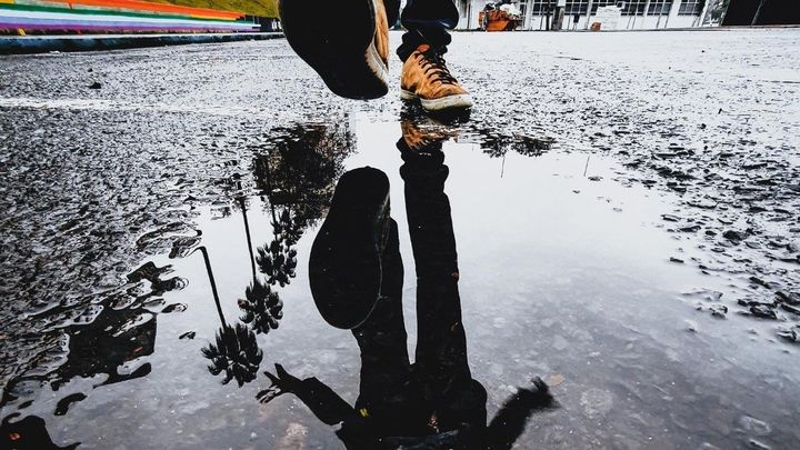 Sneakers stepping over puddle