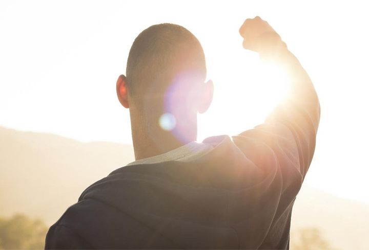 Man holding up hand in victory to the Sun