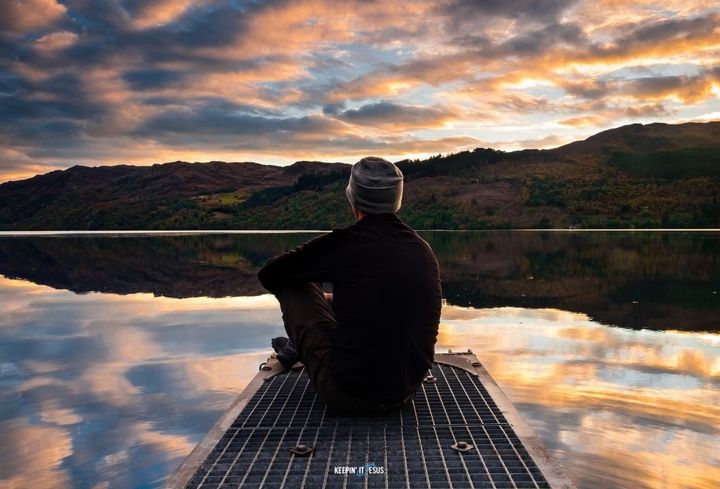 Man sitting by the lake looking into the sunset